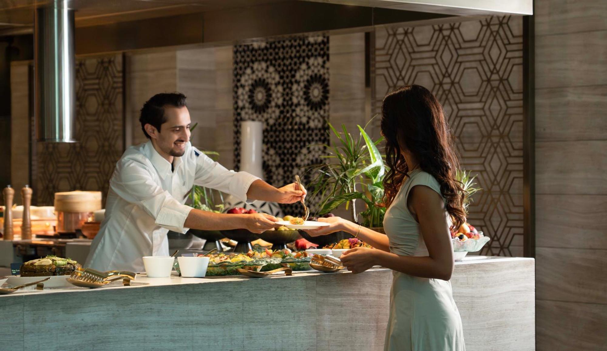 페어몬트 리야드 호텔 외부 사진 A chef serving a guest at the buffet